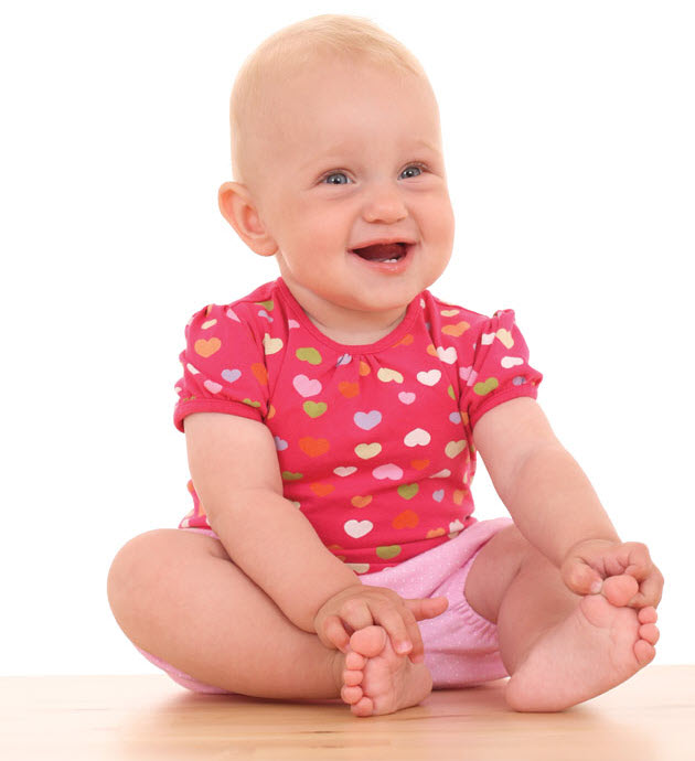 Baby smiling holding toes with mouth open