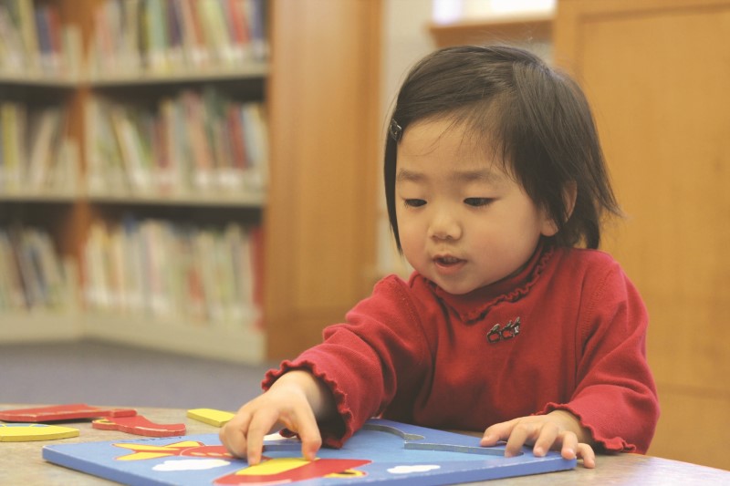young girl doing a puzzle in library