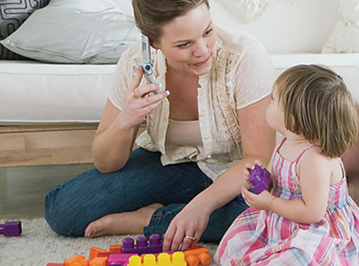 young girl plays with blocks while mom is on the phone