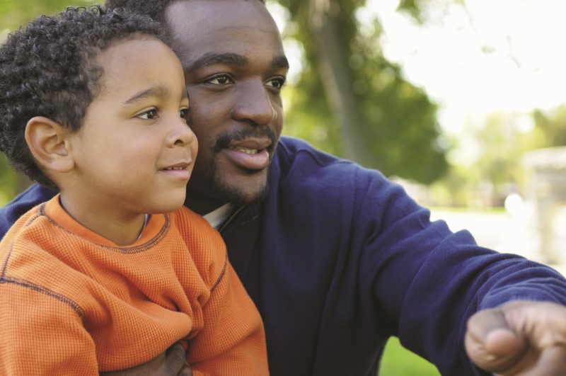 toddler sitting in dads lap outside