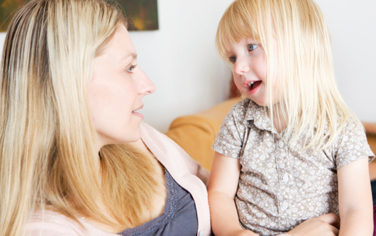 Girl sitting in her mom's lap talking