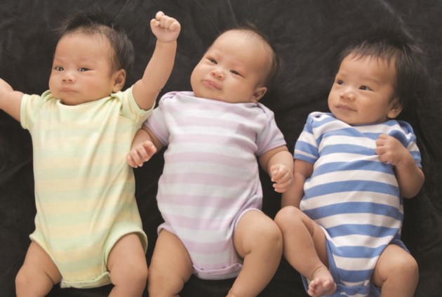 Tres bebés acostados de espalda moviendo sus brazos y piernas