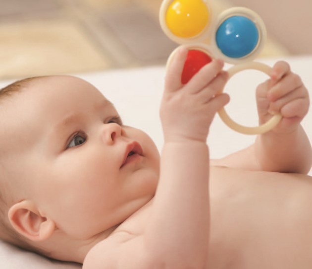 Baby lying on their back playing with a toy