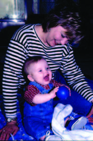 Mom watching her baby hold a ball