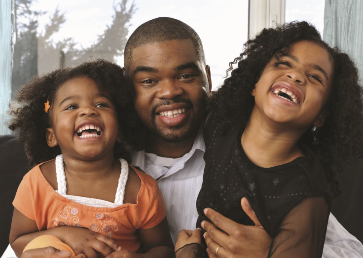 Daughters sitting on their father's lap and laughing