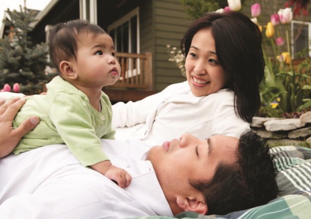 Couple outside with baby lying on dad's chest