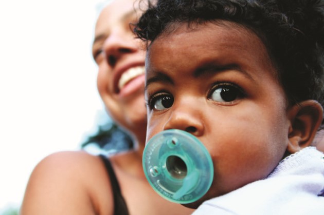 Close up baby with a pacifier and their mom