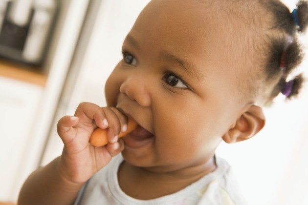 Baby eating a cooked carrot