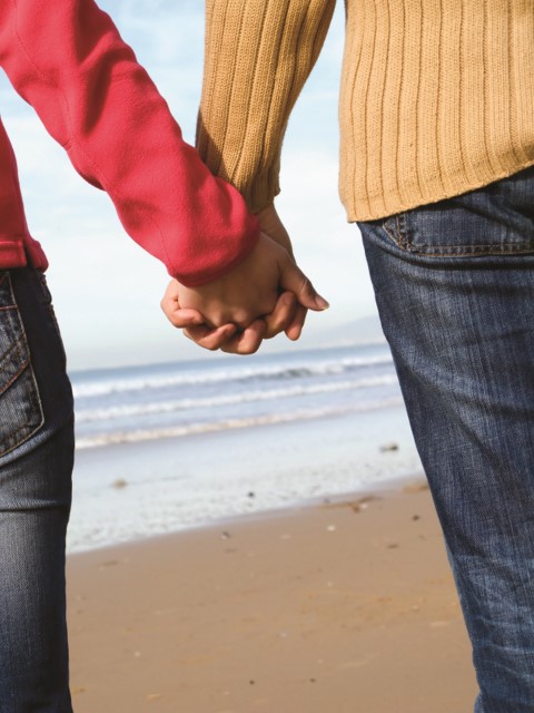 Una pareja caminando con las manos entrelazadas