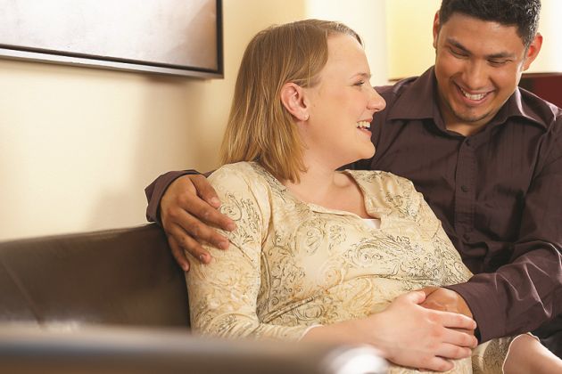 Una pareja posando sus manos sobre la barriga de la futura mamá