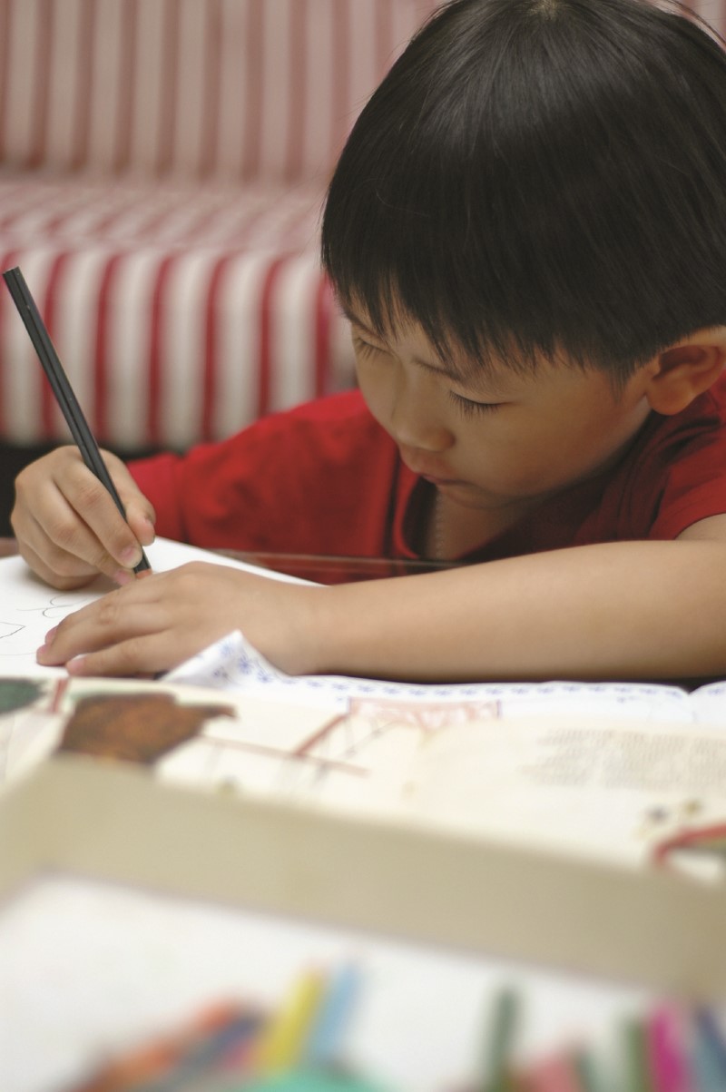 Young boy writing with a pencil