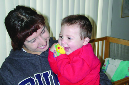 Mom holding her smiling baby with a toy
