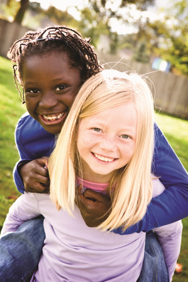 Young girl giving her friend a piggyback ride