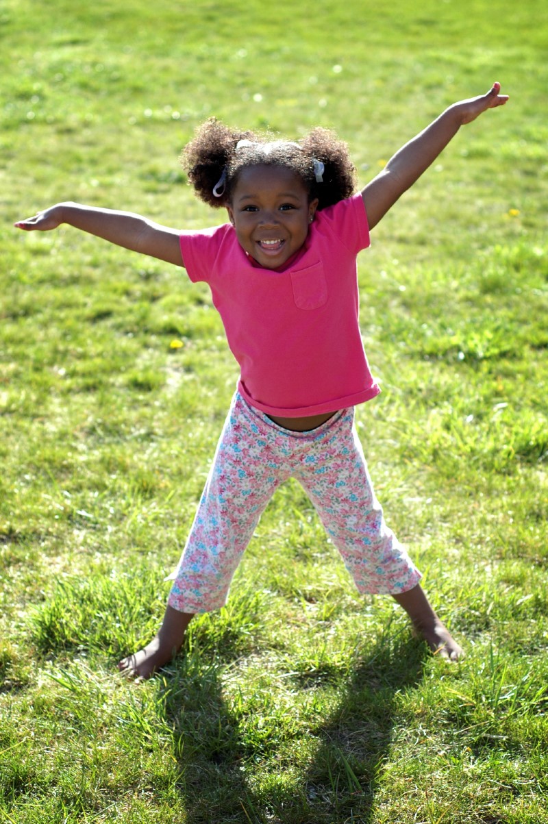 Girl jumping with her arms out in a field