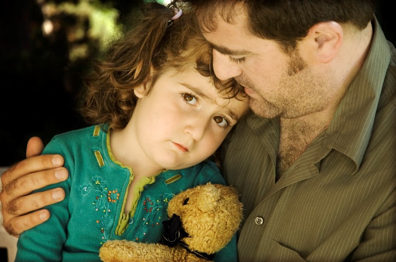 Sad girl leaning on her father's shoulder