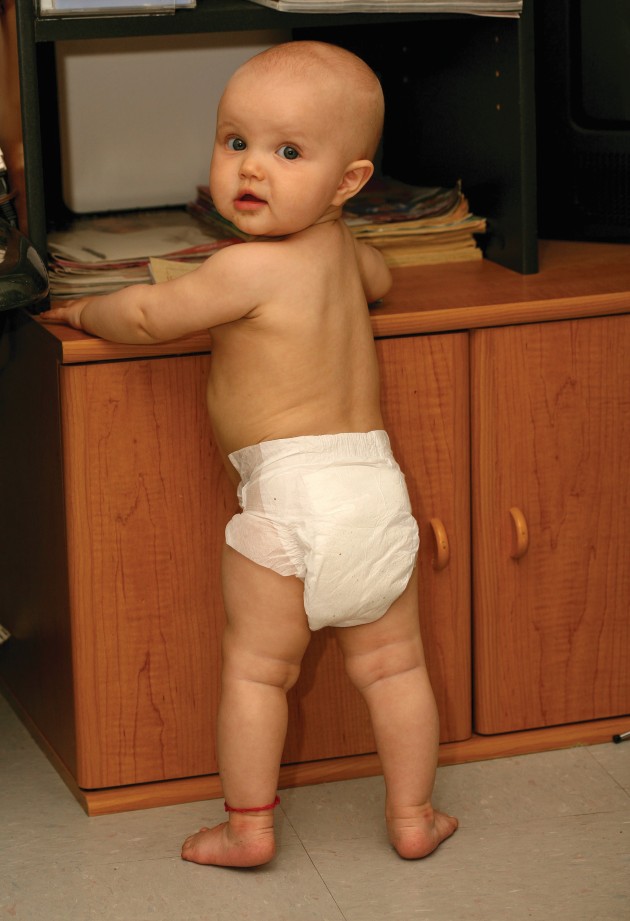 Baby standing and holding onto a tv stand