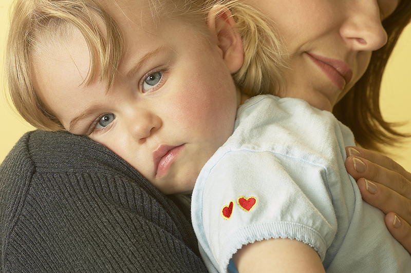Niño(a) pequeño(a) mira con ojos tristes mientras su mamá le carga