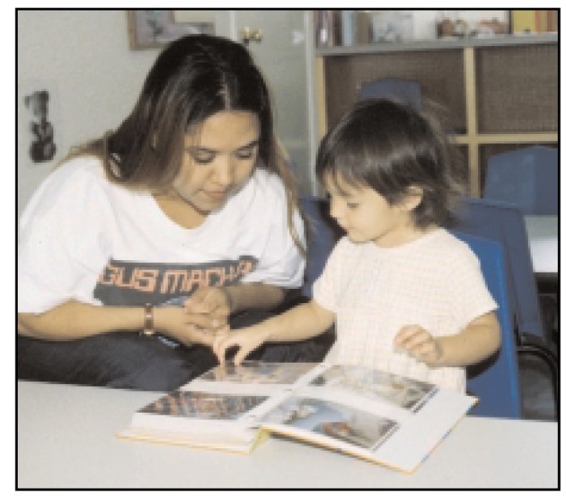 Mamá e hija observan y tocan las imágenes en las páginas de un libro o album de fotos