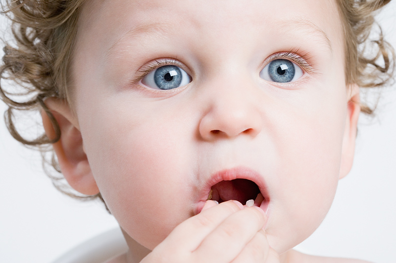 Bebé con ojos muy abiertos observa atentamente mientras sus dedos tocan sus labios