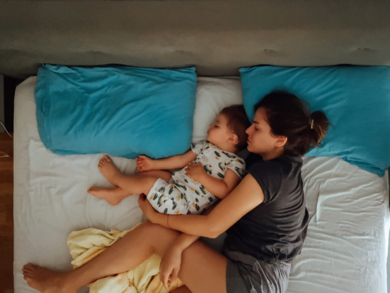 Mamá abraza a su niña ambos acostados en una cama