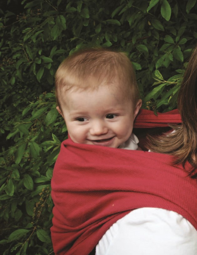 Bebé mirando a su alrededor mientras su mamá lo lleva cargado en su espalda con un portabebe
