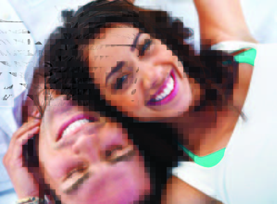 Pareja sonriente recostada de espalda con sus cabezas muy cerca la una de la otra
