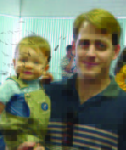 Papá de pie cargando a su bebé ambos sonrientes