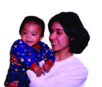 Bebé sonriente mira fijamente a alguien/algo mientras su mamá le carga