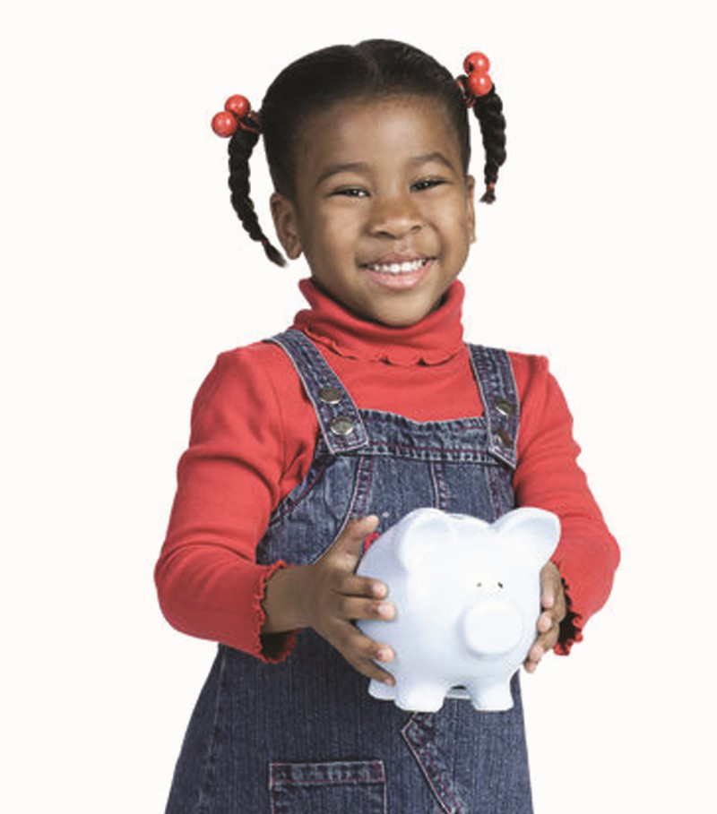 Niña pequeña sonriente sostiene de pie una alcancía/chanchito/hucha