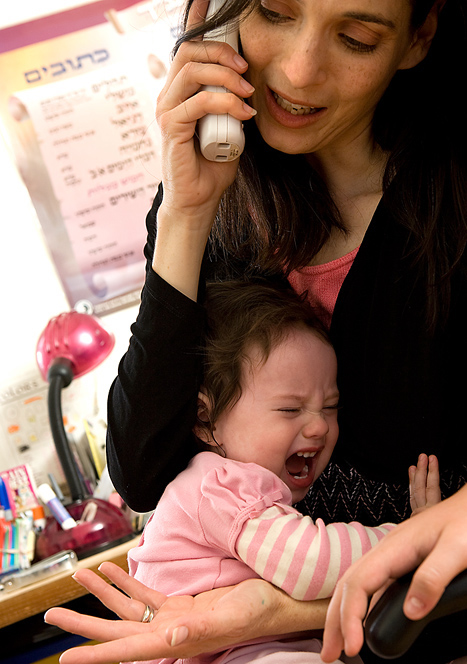 Niña pequeña llora mientras su mamá le carga mientras hablan por teléfono