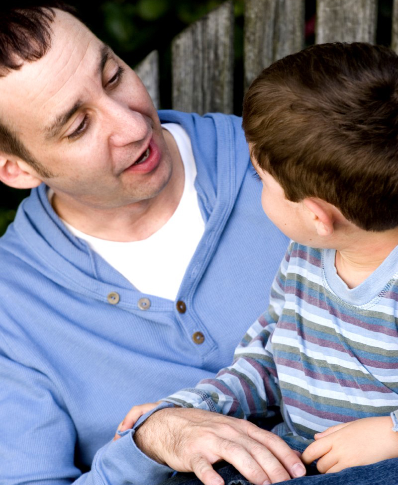 Papá e hijo(a) sonríen mientras se hablan