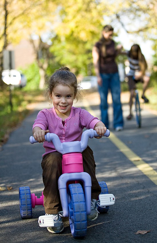Niña pequeña monta su triciclo pedaleando