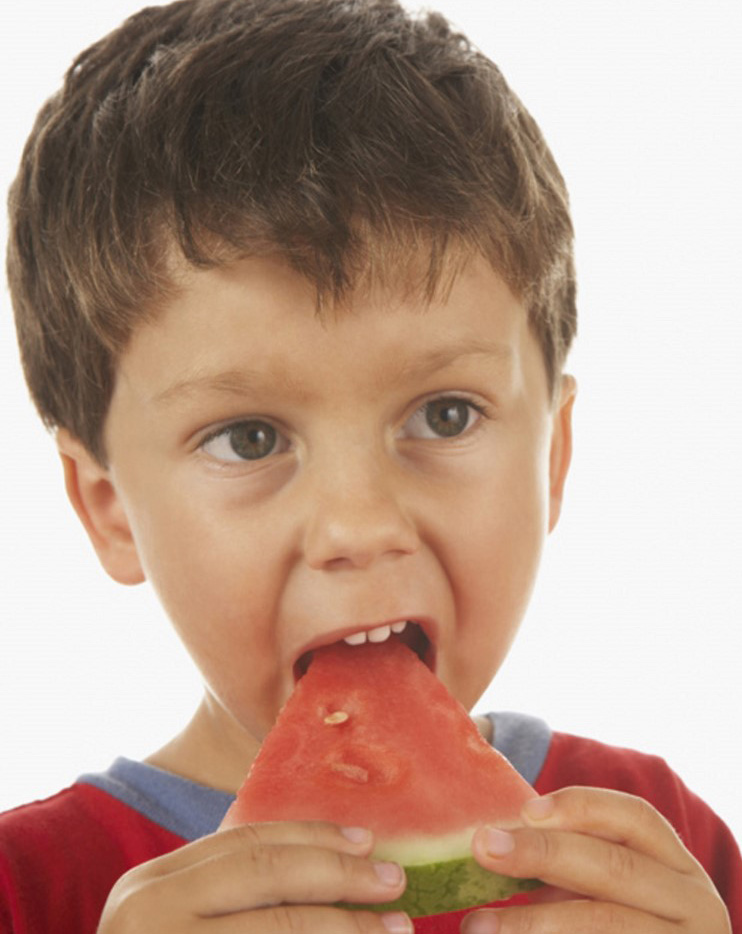 Niño pequeño come un trozo de sandía/patilla sosteniéndola con sus dos manos