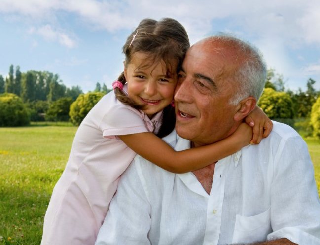 Niña pequeña abraza a su abuelo sentado en un banco