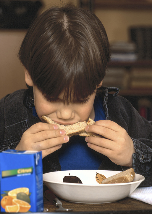 Niño pequeño comiendo desde un bol utilizando sus dos manos