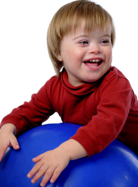Niño pequeño sonríe mientras se posa sobre una pelota grande de goma de color azul
