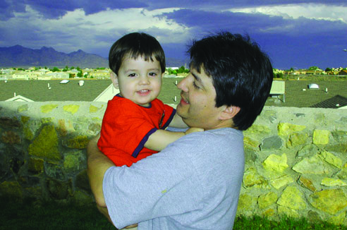 Papá cargando a su hijo mientras le observa
