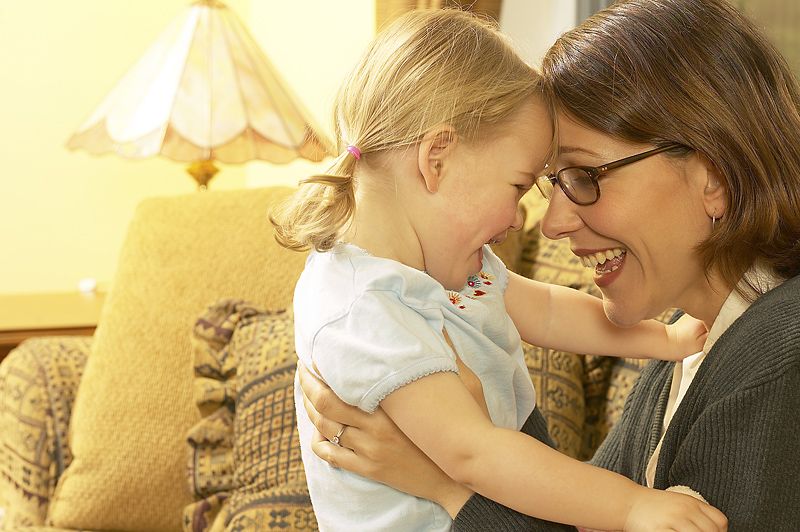 Mamá abraza a su hija pequeña juntando sus cabezas y viéndose a los ojos