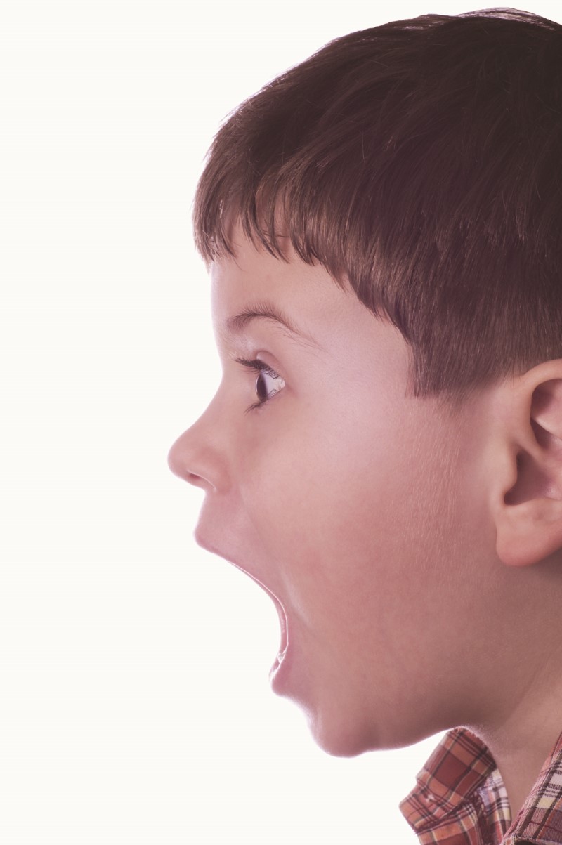 Cabeza de niño de perfil mostrando enojo con su boca muy abierta y su mirada fija