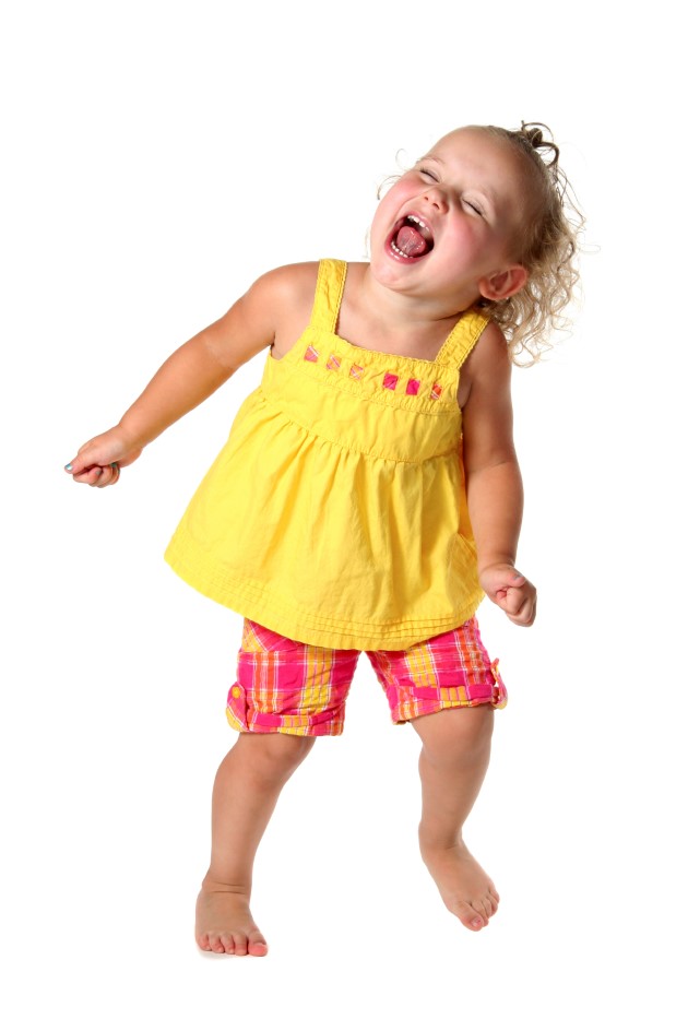 Niña pequeña vestida con tope amarillo ríe mientras baila