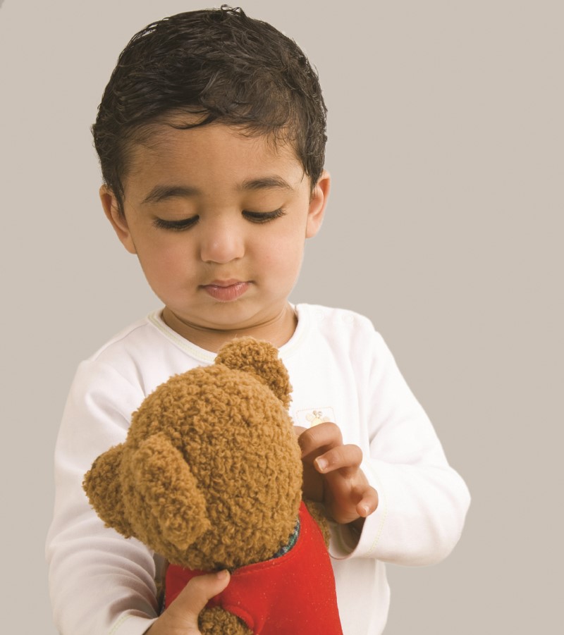 Niño pequeño observando al peluche blanco que sostiene en sus manos