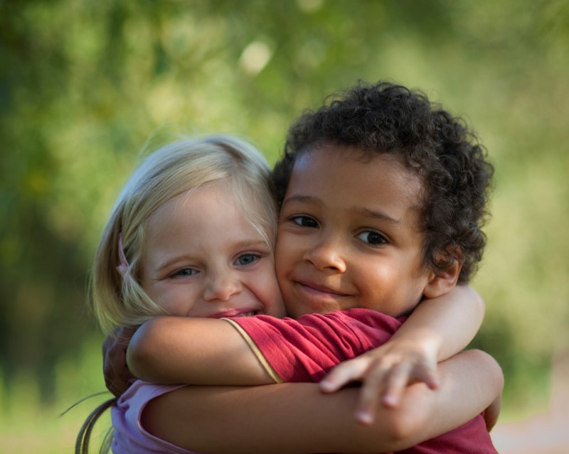 Niño y niña sonrientes se abrazan