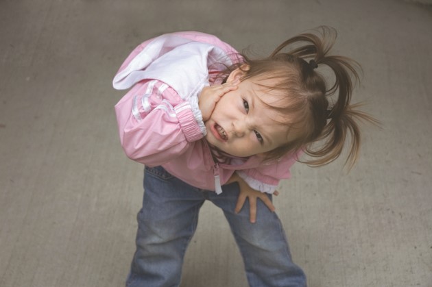 Niña pequeña se inclina de frente frunciendo su cara