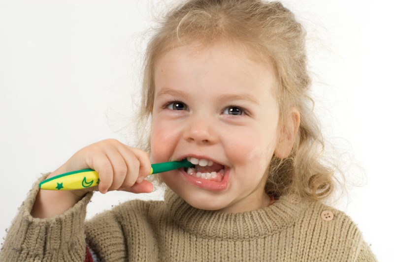 Niña pequeña sonríe mientras se cepilla sus dientes