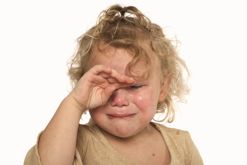 Niña pequeña cubre su cara con su manito mientras llora desconsoladamente